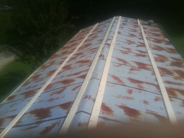 Rusted metal roof panels with new wood purlins before replacement — Storm Damage Roof Repair in Industry by Roofing Brothers