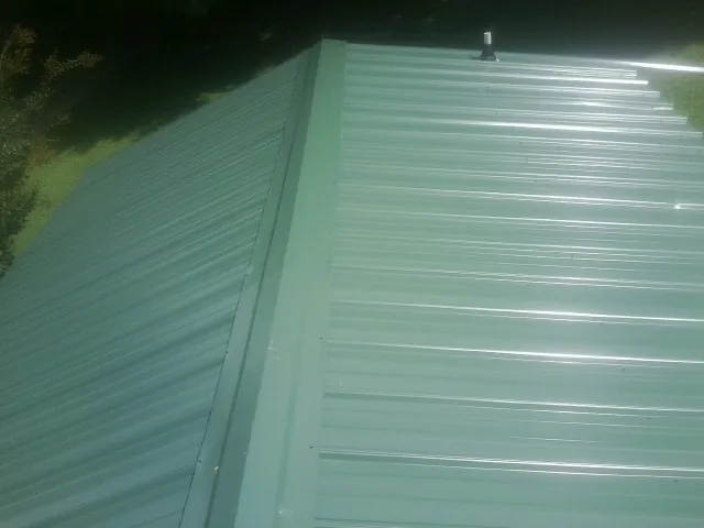 New green metal panels meeting at the ridge of a roof — Flat Roof Repair work by our crew in Industry