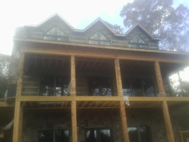 Dormers and porch framing on a large log home under construction — Roof Coating work by our crew in Industry