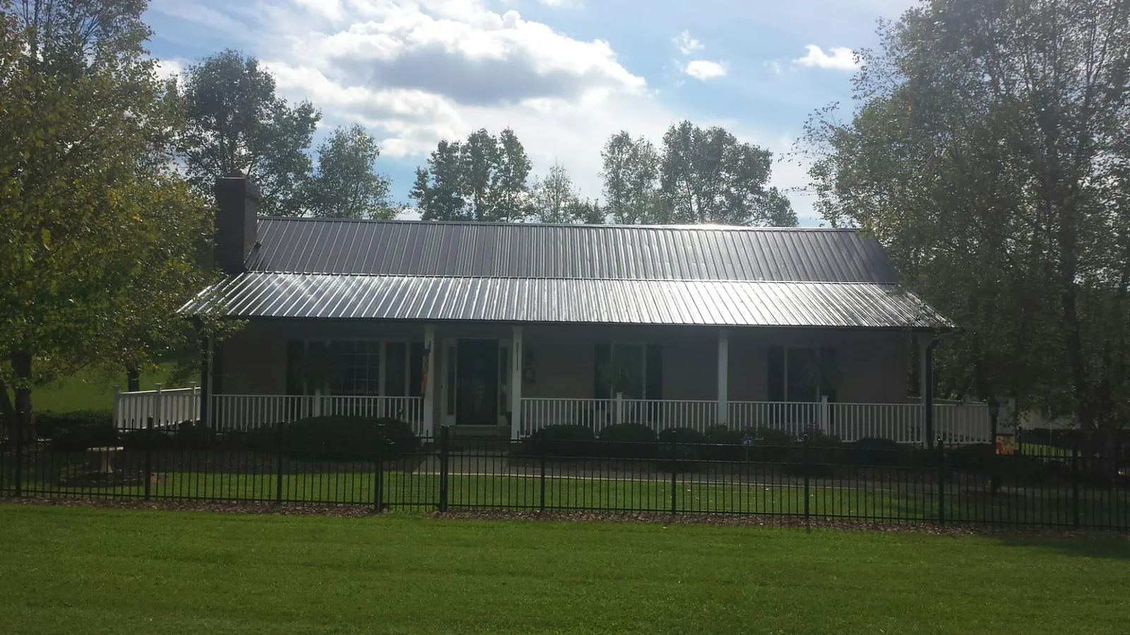 Gray metal roof on a brick ranch with a full width front porch — Gutter Guard Installation work by our crew in Industry